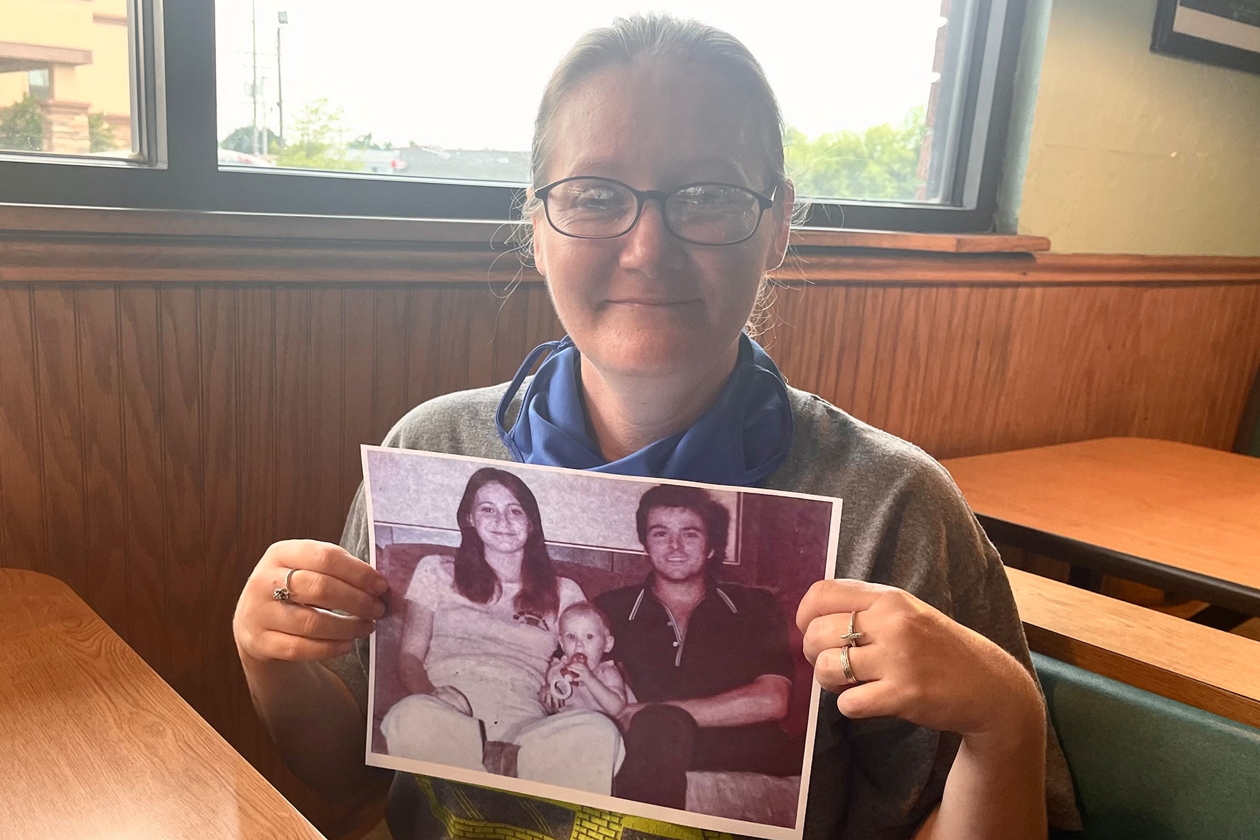 Holly Marie Clouse holding a photo of her and her parents