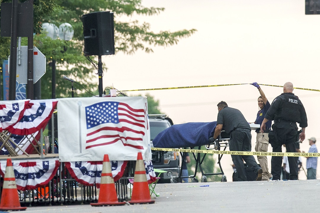 A body is transported from the scene of a mass shooting during the July 4th parade