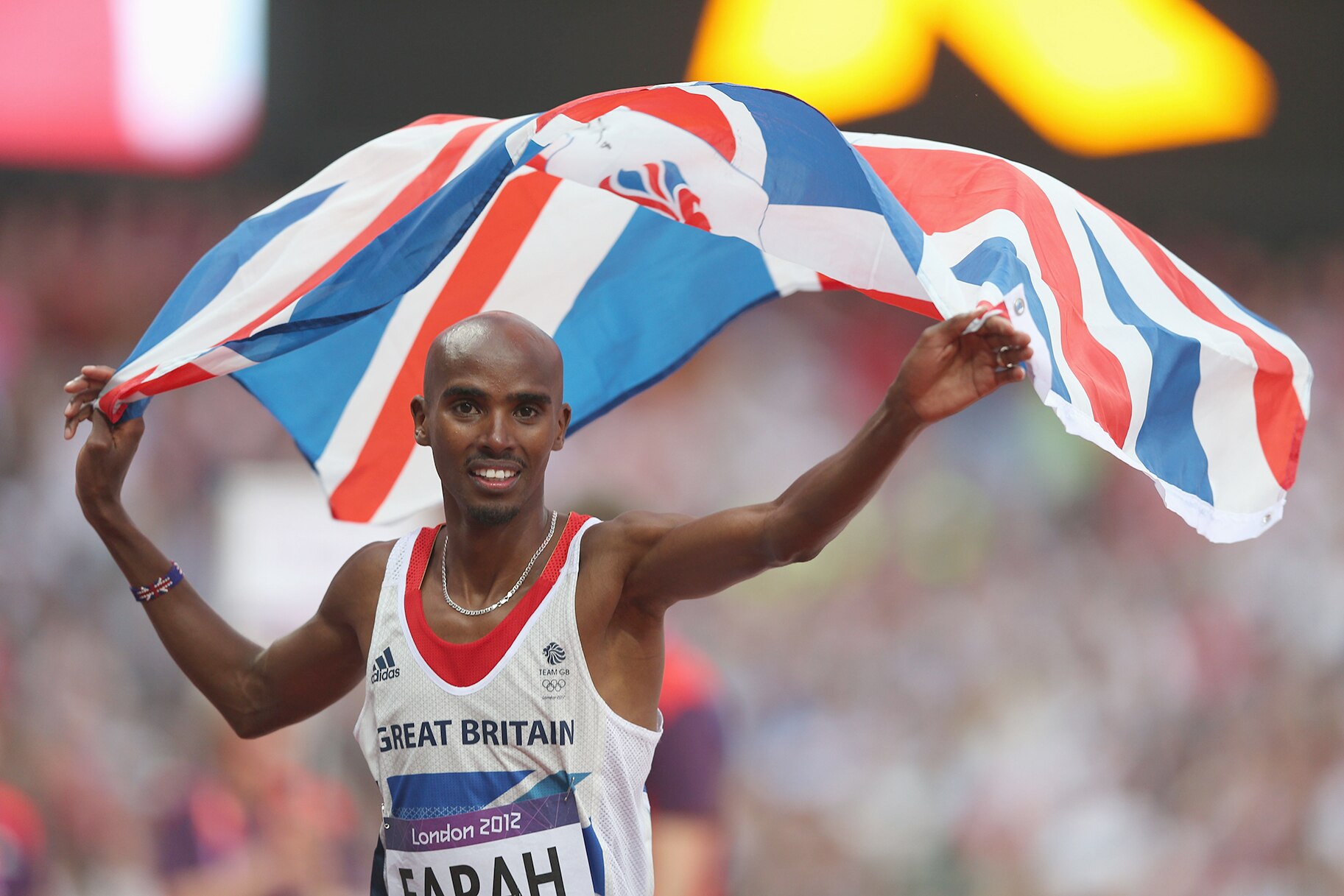 Mohamed Farah of Great Britain holds a union jack aloft as he celebrates winning gold