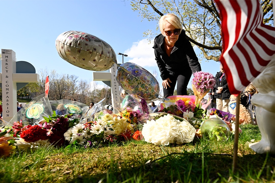 A woman leaves flowers at a growing memorial in Nashville, at an entry to Covenant School.