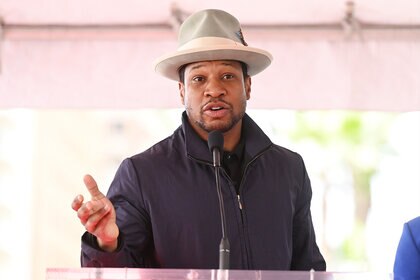 An image of Jonathan Majors speaking at a podium