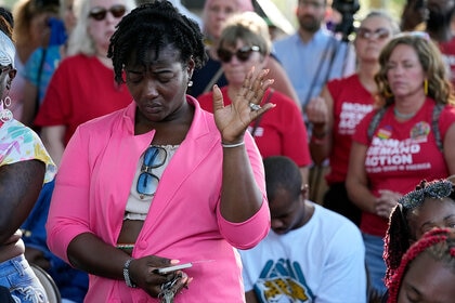 A woman attending a vigil for the victims of Saturday's mass shooting bows her head in prayer Sunday, Aug. 27, 2023, in Jacksonville, Fla.