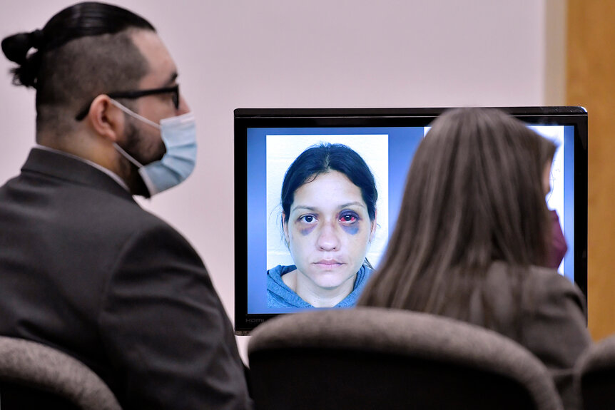 An image of Britany Barron is shown as her husband Armando Barron looks toward the jury