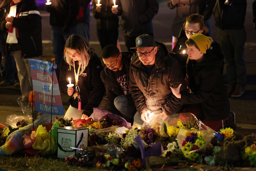 People hold a vigil at a makeshift memorial near Club Q night club