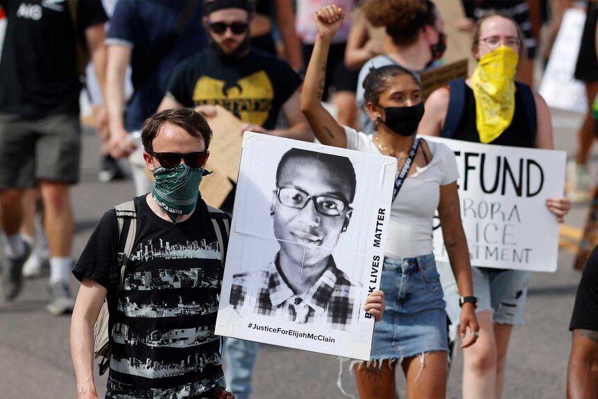 People carrying posters with Elijah Mcclain's face during a Protest